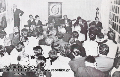 Φωτογραφία από την συναυλία του Μάρκου Βαμβακάρη, από την έκθεση Ρεμπέτικα τραγούδια- τεκμήρια, στο Χίλτον. Μαζί του είναι οι γιοί του Στέλιος και Δομένικος και ο Κερομύτης (8-5-1968)