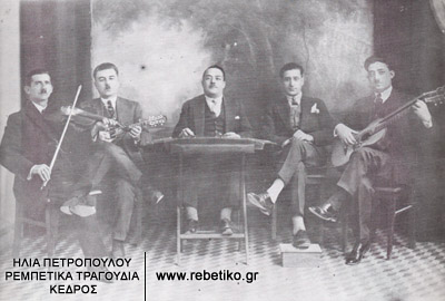 Ο Νίκος Συρίγος ο σαντορινιός, ο Μιχάλης Σκουλούδης (μαντολίνο), ο Γιώργος Πετρίδης (τσίμπαλο), ο τότε διάσημος Κώστας Νούρος (με το περίφημο υποπόδιόν του) κι ο Στελάκης ο Περπινιάδης (τραγούδι-κιθάρα), σε φωτογραφία του 1928