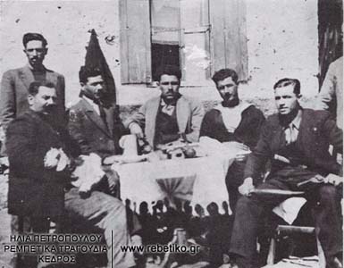 Ο Μαρίνος ο Μουστάκιας, ο Σινιακός (όρθιος), ο Κίτσος Σάβας, ο Τζανής ο Ψαράς, ο Μιχάλης Μπεσάκος κι ο Νίκος ο Τρελάκιας, πάνοπλος, ενώ τρώνε στο σπίτι του Μάθεση (1934)