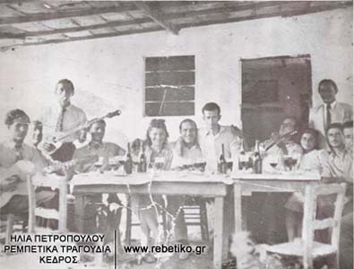 Ο Τσανάκας, ο Καλδάρας (όρθιος), η Ζωή Τσιτσάνη, ο μαγαζάτορας, ο Βασίλης Τσιτσάνης, ο Στράτος με την γυναίκα του και τρεις φίλοι. Γλεντι στο Ασβεστοχώρι Θεσσαλονίκης, το καλοκαίρι του 1940. Ο Τσιτσανής είναι κουρεμένος, γιατί υπηρετεί στον στρατό.